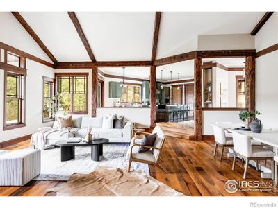 The living room makes a dramatic first impression with 150-year-old reclaimed oak floors, a handsome stone fireplace and soaring beamed ceilings supported by hand-hewn yellow pine beams. | Image 3