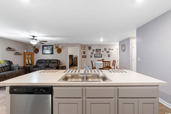 Kitchen with ceiling fan, a kitchen island with sink, hardwood / wood-style flooring, dishwasher, and sink | Image 13