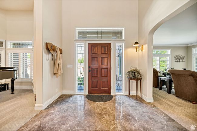 Foyer entrance with arched walkways, a high ceiling, carpet floors, marble finish flooring, and crown molding | Image 18