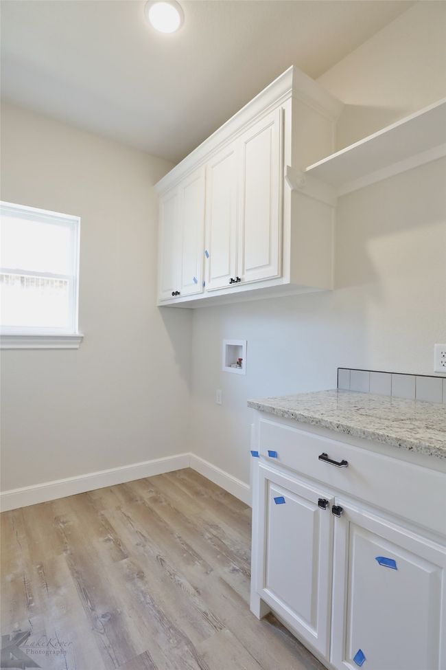 Washroom with cabinet space, hookup for a washing machine, and light wood-style flooring | Image 31
