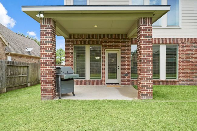Cozy backyard patio with a covered area, featuring sturdy brick pillars and a grill. Perfect for outdoor gatherings, it opens to a well-maintained lawn and provides a comfortable space for relaxation. | Image 34