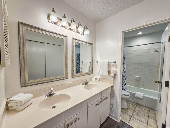 Bathroom featuring double vanity, toilet, shower / bathtub combination with curtain, and a textured ceiling | Image 24