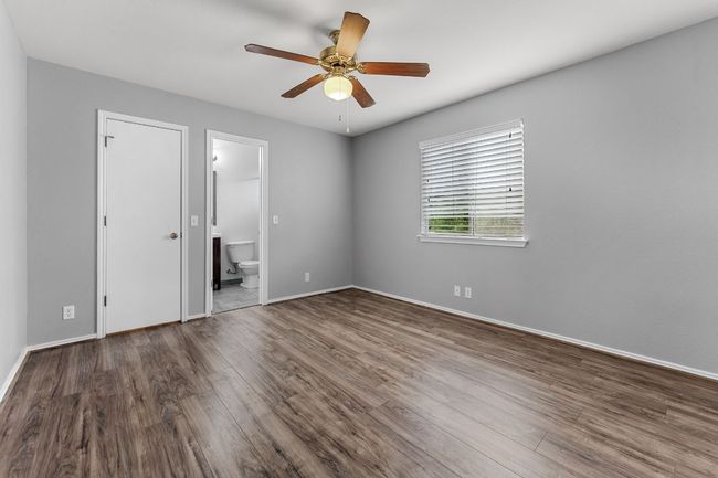 Primary Bedroom with wood finished floors, connected bathroom, and a ceiling fan | Image 12