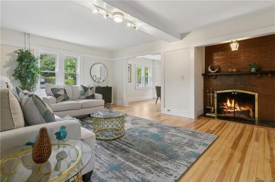 Living room featuring beam ceiling, a brick fireplace, rail lighting, and light wood-type flooring | Image 3