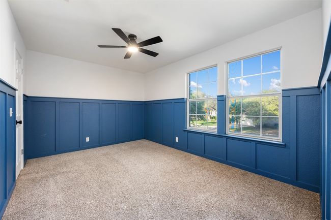 Empty room with a decorative wall, carpet flooring, a wainscoted wall, and ceiling fan | Image 32