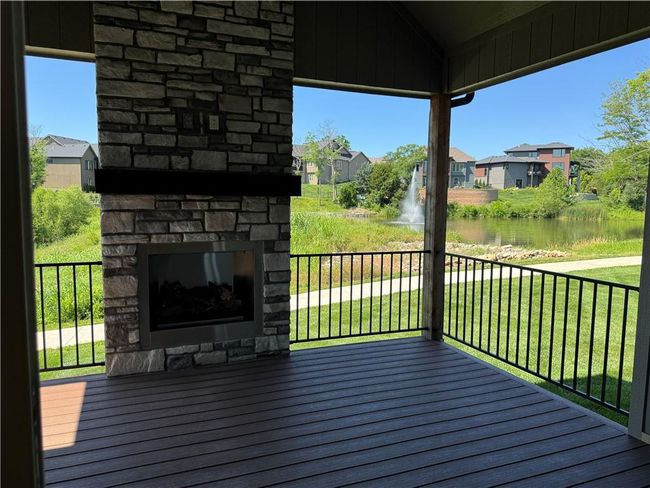 Wooden deck with an outdoor stone fireplace, a water view, a residential view, and a yard | Image 12