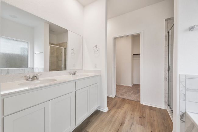 Full bath featuring a shower stall, double vanity, wood finished floors, and a spacious closet | Image 21