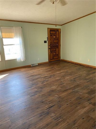 Unfurnished room with ornamental molding, ceiling fan, a textured ceiling, and dark hardwood / wood-style flooring | Image 2