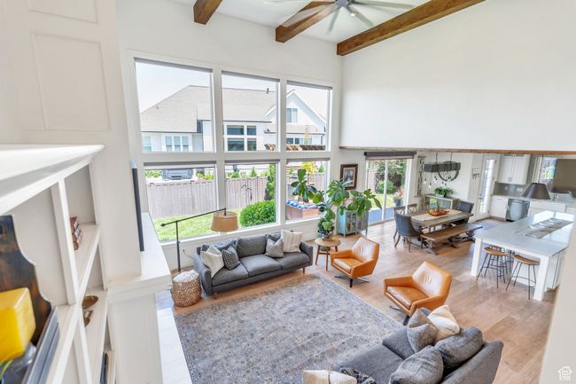 Living room featuring a high ceiling, a ceiling fan, beam ceiling, and wood finished floors | Image 39