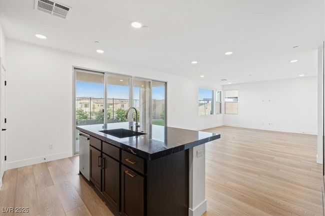 Kitchen featuring a sink, light wood-style floors, visible vents, dishwasher, and an island with sink | Image 28