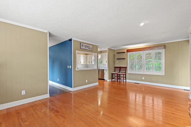 Unfurnished living room with baseboards, crown molding, visible vents, and light wood-type flooring | Image 5