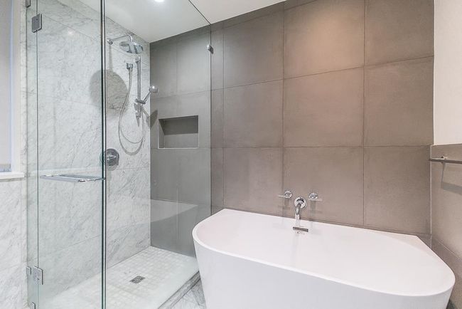 Bathroom with a shower stall, a soaking tub, and tile walls | Image 19