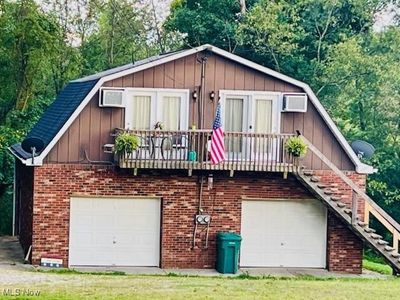 View of front of house with a wall mounted air conditioner and a garage | Image 1