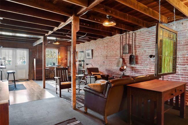 Carpeted living room featuring beam ceiling and brick wall | Image 13