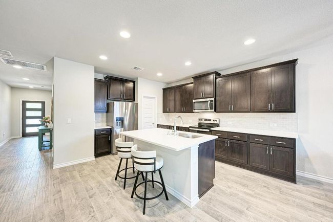 Kitchen with stainless steel appliances, light wood-type flooring, dark brown cabinetry, and recessed lighting | Image 4