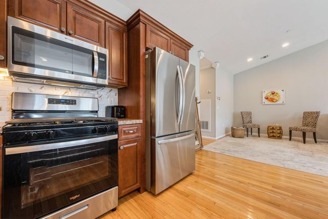 Kitchen featuring decorative backsplash, stainless steel appliances, light wood-style flooring, lofted ceiling, and visible vents | Image 8