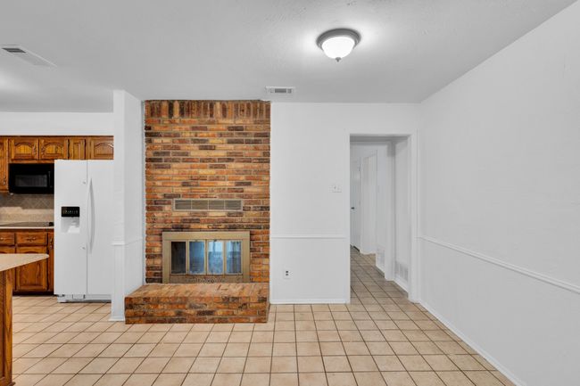 Unfurnished living room with visible vents, a brick fireplace, and light tile patterned flooring | Image 12