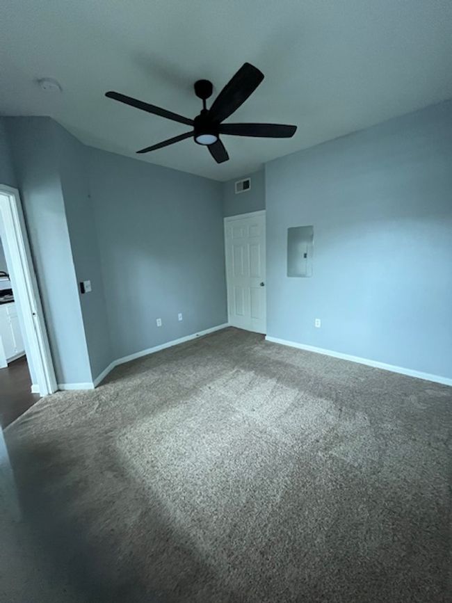 Unfurnished bedroom featuring dark carpet, visible vents, a ceiling fan, electric panel, and baseboards | Image 19