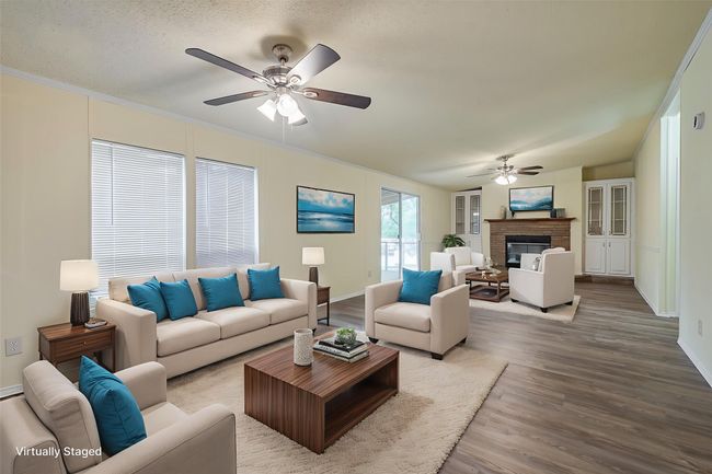 Living area featuring a ceiling fan, wood finished floors, a fireplace, baseboards, and crown molding | Image 6