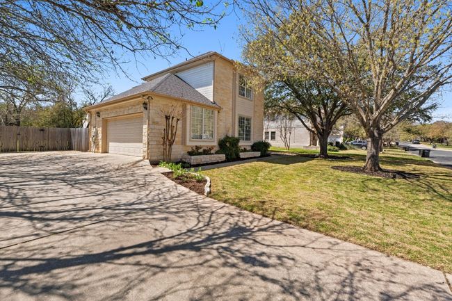 View of front facade featuring fence, driveway, an attached garage, a front lawn, and stone siding | Image 4