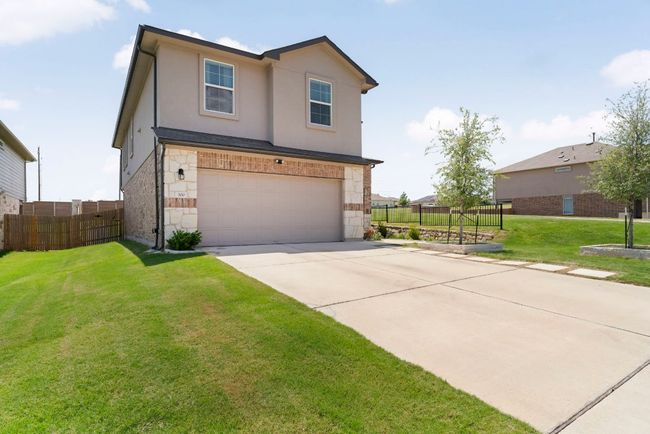 Traditional-style home featuring stone siding, an attached garage, concrete driveway, and stucco siding | Image 33