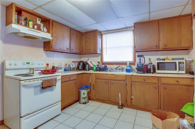 3rd unit Kitchen; featuring a paneled ceiling, sink, light tile patterned floors, and white appliances | Image 41