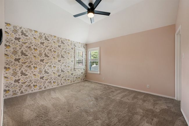 Bedroom with one wallpapered accent wall, a ceiling fan, and a walk-in closet. | Image 27