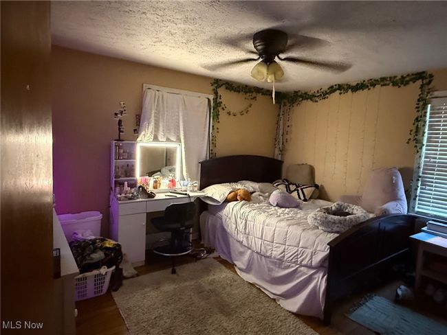Bedroom featuring ceiling fan, wood finished floors, and a textured ceiling | Image 6