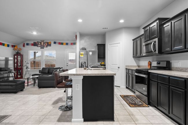Kitchen featuring a sink, appliances with stainless steel finishes, open floor plan, visible vents, and dark cabinets | Image 9