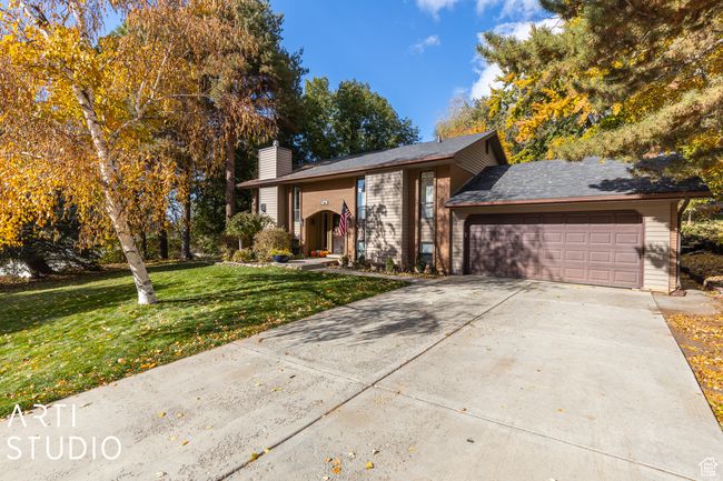 View of front of property with a chimney, an attached garage, brick siding, a front yard, and concrete driveway | Image 43