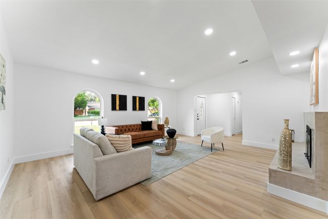 Living room with light wood-style floors, a premium fireplace, recessed lighting, and lofted ceiling | Image 5