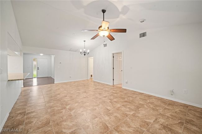 Spare room with ceiling fan, a chandelier, and high vaulted ceiling | Image 11