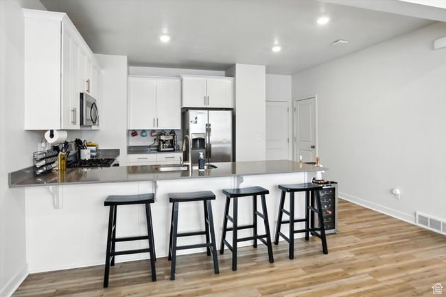 Kitchen featuring stainless steel appliances, a peninsula, new light wood-style LVP floors, a kitchen bar, and recessed lighting | Image 27