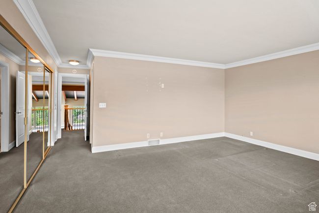 Spare room featuring crown molding and dark colored carpet | Image 22