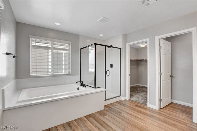 Bathroom with a bath, a stall shower, a spacious closet, wood finished floors, and baseboards | Image 43