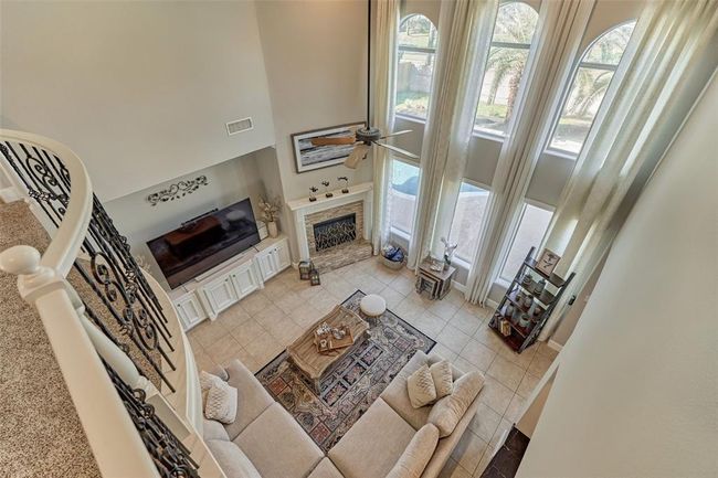Bright living room with a cozy fireplace and large windows offering abundant natural light and views of the resort-style backyard. | Image 8