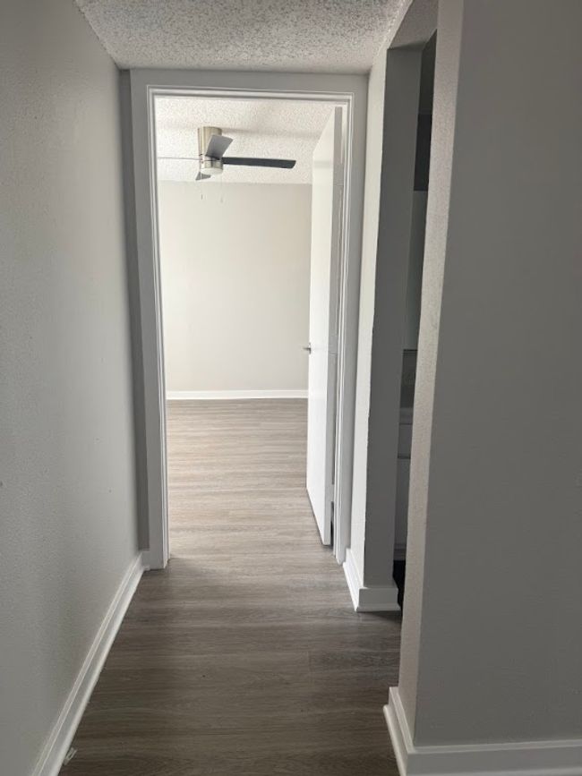 Corridor featuring a textured ceiling, wood finished floors, and baseboards | Image 10