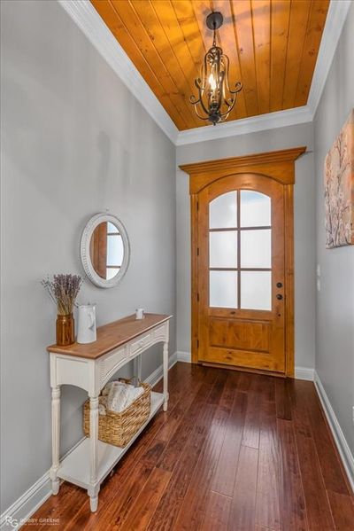 Foyer entrance with wooden ceiling, ornamental molding, wood flooring, and a chandelier | Image 2