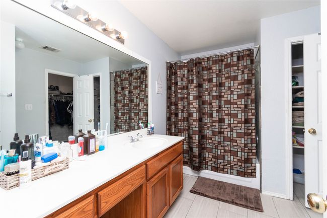 Bathroom featuring visible vents, a spacious closet, curtained shower, and vanity | Image 12