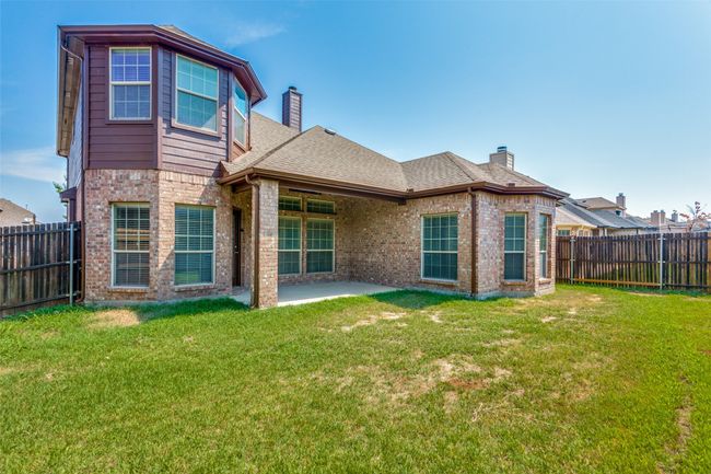 Rear view of house featuring a chimney, brick siding, a fenced backyard, and roof with shingles | Image 34