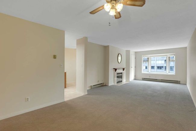 Unfurnished living room featuring a baseboard radiator, a baseboard heating unit, a ceiling fan, and light colored carpet | Image 11