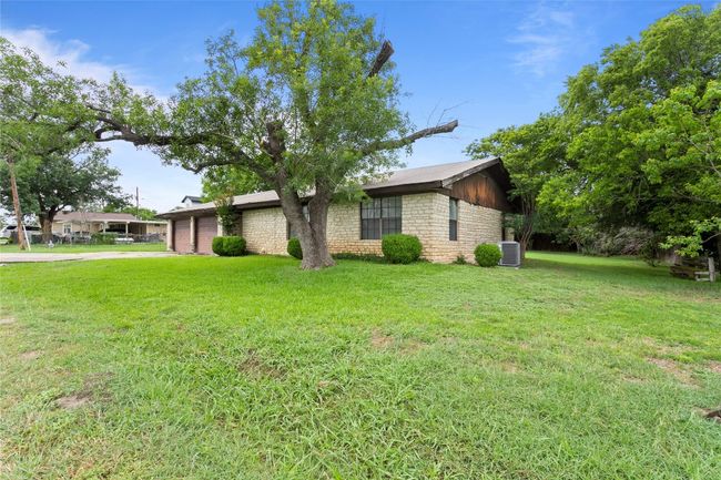 View of property exterior with a garage, concrete driveway, a lawn, and stone siding | Image 29