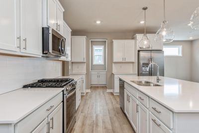 (Photo of a similar home, actual home's finishes will vary slightly) Welcome to the Birmingham! This spacious kitchen features a large center island, quartz countertops, under mount sink, LVP wood floors and stainless appliances. | Image 3