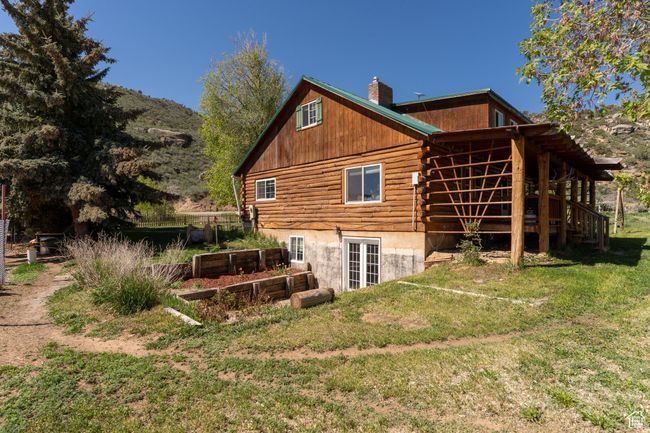Rear view of property featuring log exterior, a yard, a chimney, a vegetable garden, and a deck | Image 5