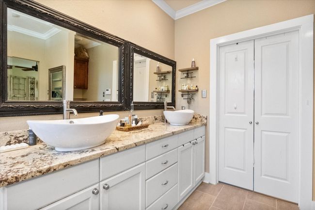 Bathroom with ornamental molding, double vanity, tile patterned floors, and ceiling fan | Image 16