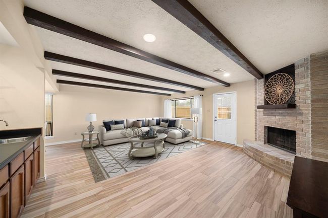 Direct backyard access and a corner brick fireplace make this room both functional and inviting for gatherings or movie nights. This photo has been virtually staged. | Image 16