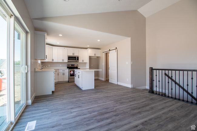 Kitchen featuring dark wood finished floors, a barn door, visible vents, white cabinetry, and appliances with stainless steel finishes. *Photo in picture is similar to the home being built | Image 4