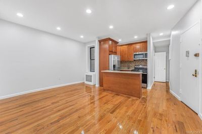 Kitchen with backsplash, a kitchen island, appliances with stainless steel finishes, and light wood-type flooring | Image 1