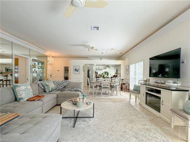 Tiled living room with ceiling fan with notable chandelier and crown molding | Image 30