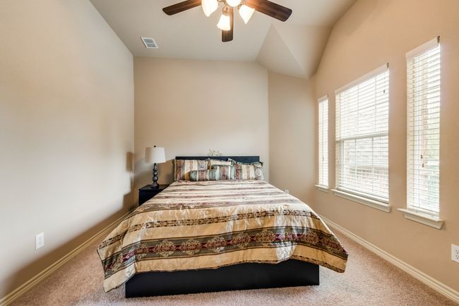 Carpeted bedroom featuring a ceiling fan, vaulted ceiling, and baseboards | Image 20